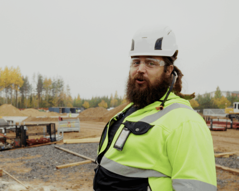 Kyp&auml;r&auml;&auml;n ja huomiotakkiin pukeutunut henkil&ouml; rakennusty&ouml;maalla.